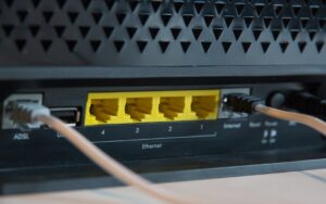 A technician checks network cables connected to a modem and wireless router on a residential desk.