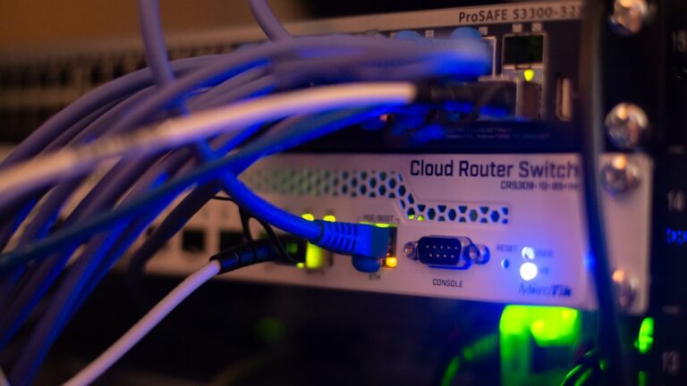 A person connects a laptop to a router using an Ethernet cable on a home desk.